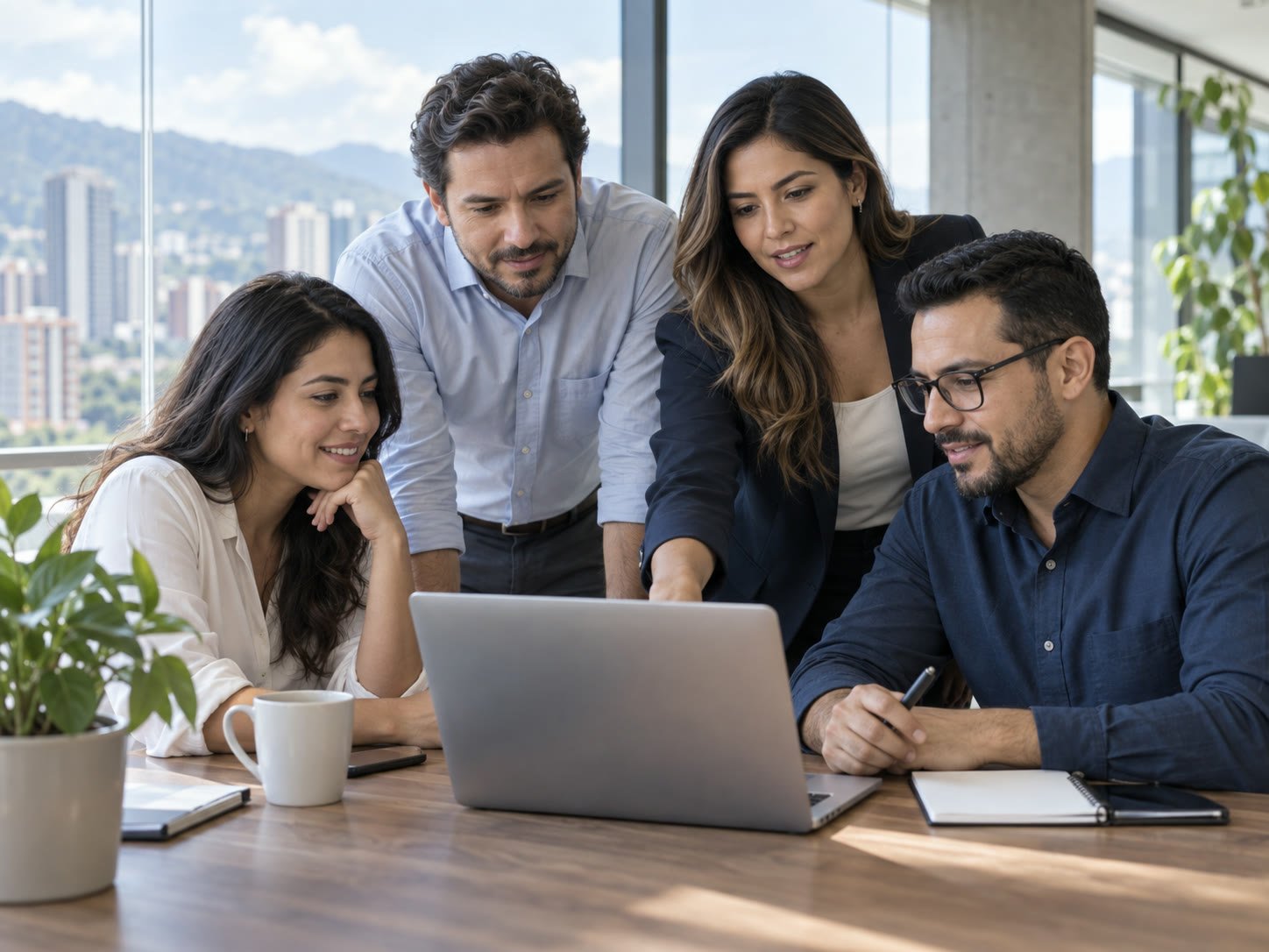 Equipo de CloudTec Digital colaborando alrededor de un computador portátil